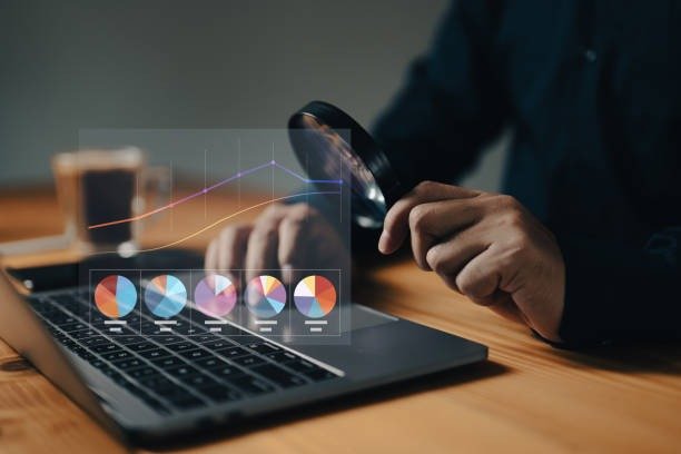 Professional reviewing digital marketing performance data and roi on a laptop with charts and magnifying glass.