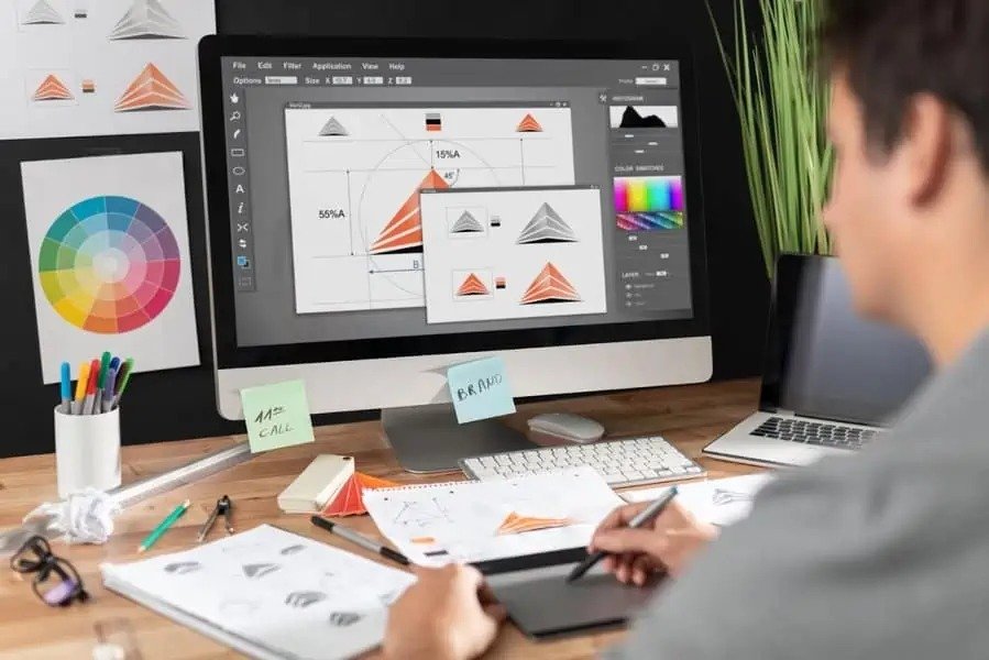 Image showing a graphic designer developing brand identity visuals, color palettes, and logo variations on a computer, featured in the article “Best graphic design services in Dubai for social media and websites.”